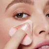 Model using powder puff to apply makeup